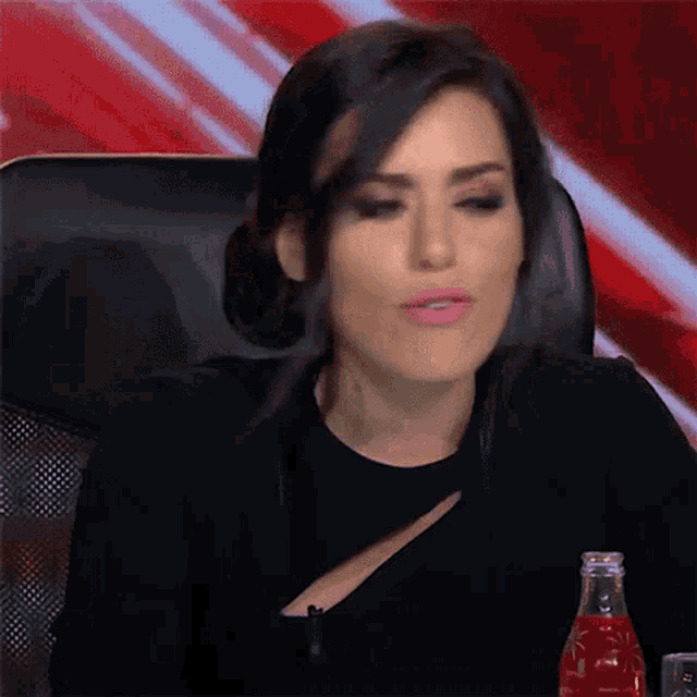 a woman is sitting in a chair with a bottle of soda next to her .