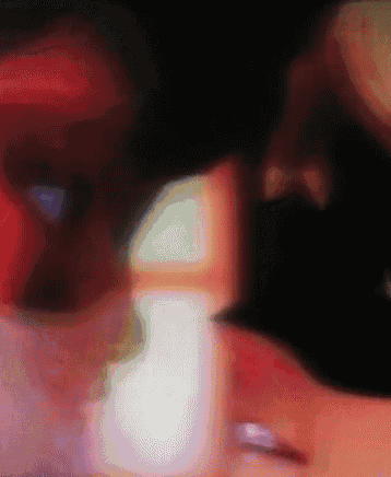 a blurry picture of a person 's face with a purple ring on their finger
