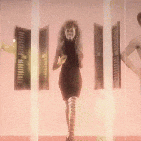 a woman in a black dress is walking through a room with shutters