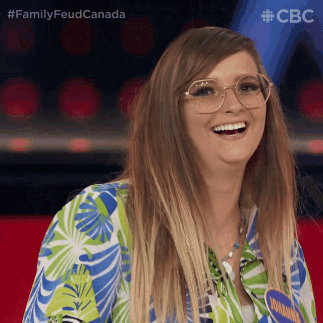 a woman wearing glasses and a hawaiian shirt is smiling for the camera