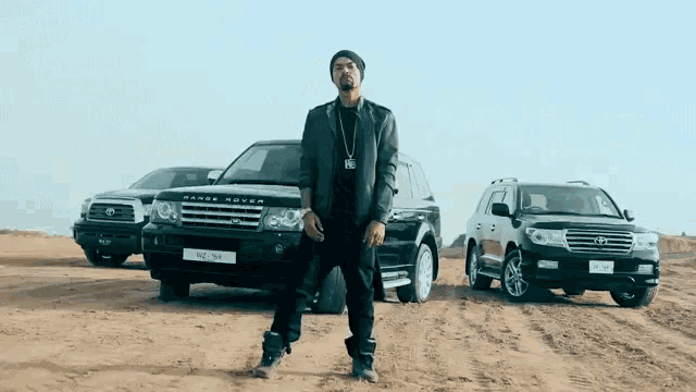 a man stands in front of a range rover and a toyota
