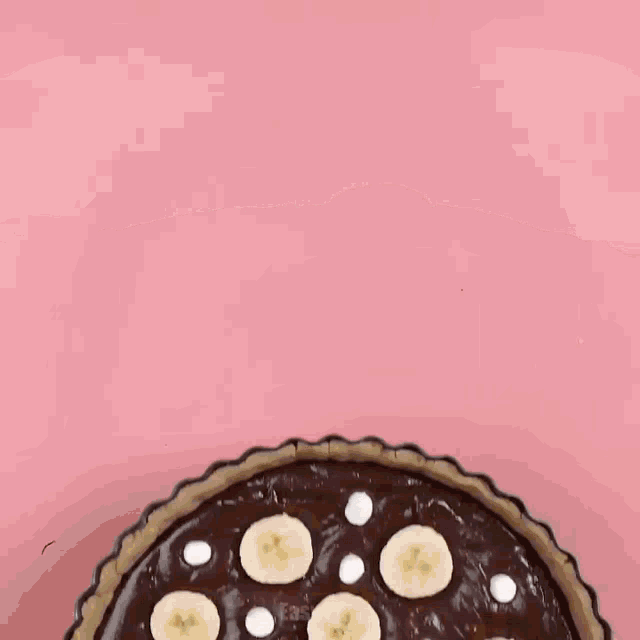 a chocolate pizza with banana slices on top is sitting on a wooden cutting board