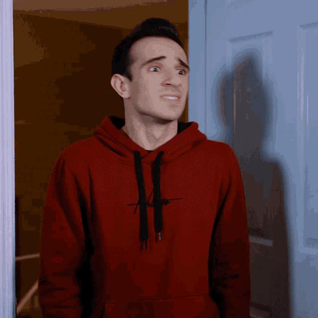 a man wearing a red hoodie with a black letter h on it