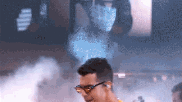 a man wearing glasses and headphones is standing in a room with smoke coming out of it