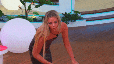 a woman in a black dress is kneeling down on a wooden deck