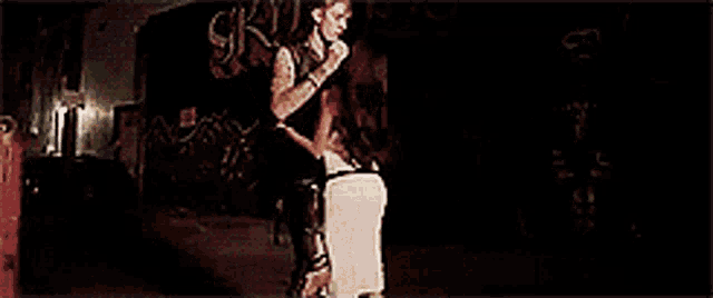 a man is standing next to a woman on a skateboard in a dark room with graffiti on the walls