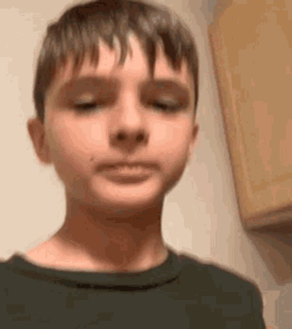 a close up of a young boy making a funny face .