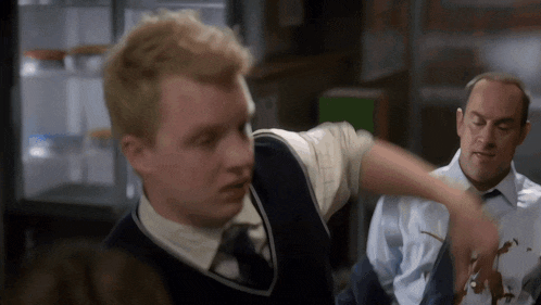 a man in a vest and tie is pointing