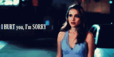 a woman in a blue dress stands in front of a sign that says i hurt you i 'm sorry