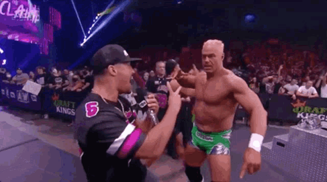 a wrestler is talking to a referee in a wrestling match .