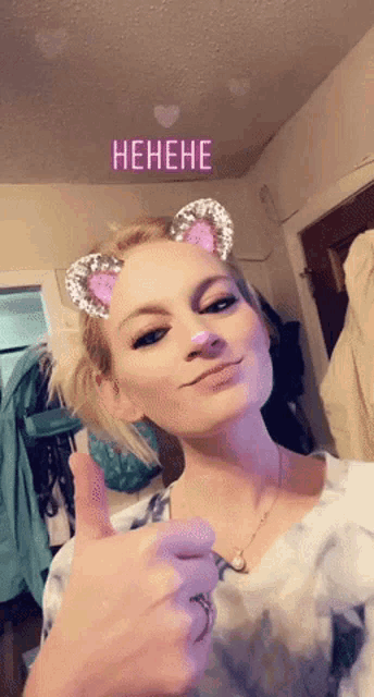 a woman giving a thumbs up with a filter that says ' henehe '