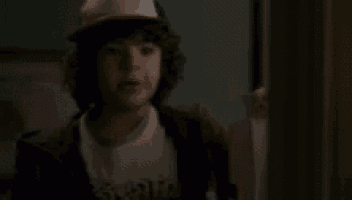 a young boy wearing a hat and a t-shirt is standing in a doorway .