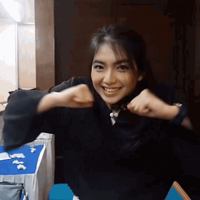 a woman wearing a black sweater and a watch is smiling with her arms outstretched