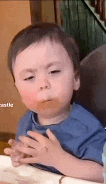 a baby is sitting in a high chair eating a sandwich .