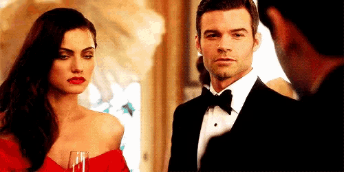 a man in a tuxedo and a woman in a red dress are standing next to each other in a room .