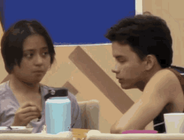 a man and a woman are sitting at a table with a blue water bottle in front of them