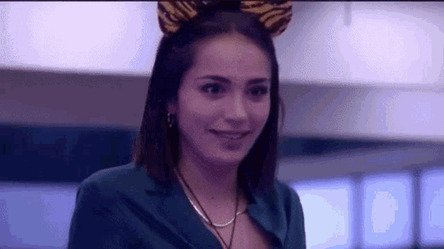 a woman wearing a tiger ears headband and a green jacket is smiling .