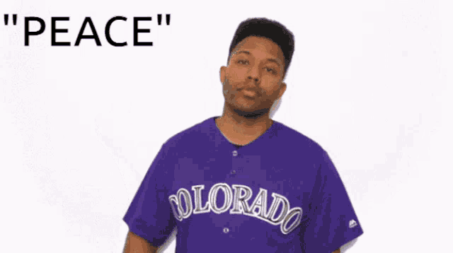 a man wearing a purple colorado jersey is giving a peace sign