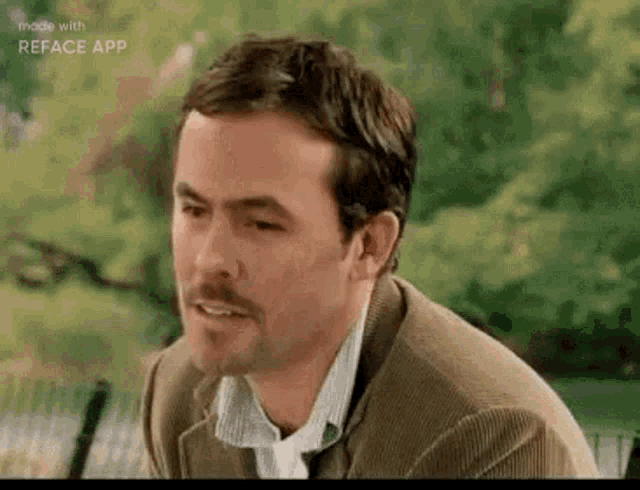a man with a beard wearing a suit and tie is sitting on a bench .