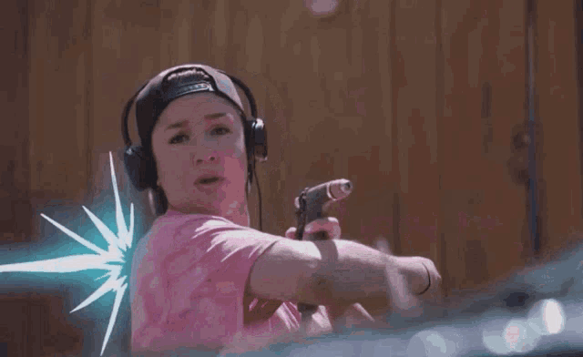 a girl in a pink shirt is holding a hose with a purple light coming out of it