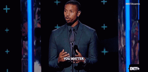 a man in a suit and tie is giving a speech in front of a microphone .