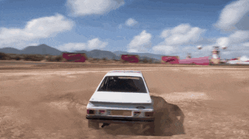 a white car driving through a dirt field with mountains in the background