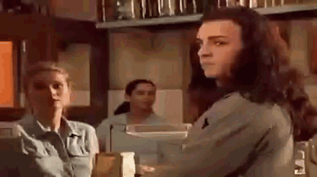 a woman is standing in a kitchen talking to another woman .