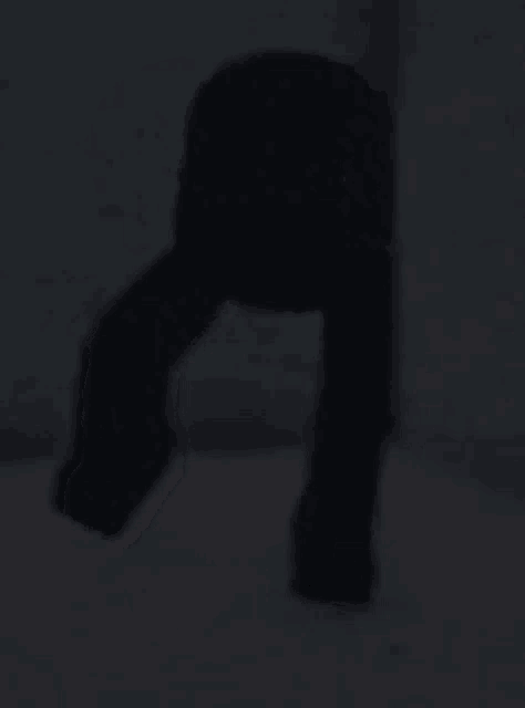 a silhouette of a person standing in the dark with their legs crossed .