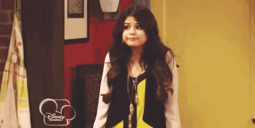 a woman is standing in front of a yellow door wearing a yellow and black vest .