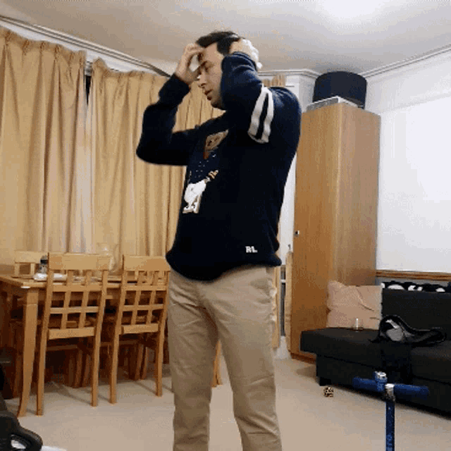 a man wearing a sweater that says rl is standing in a living room