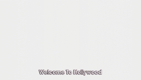 a man and woman are standing in front of a screen that says welcome to hollywood