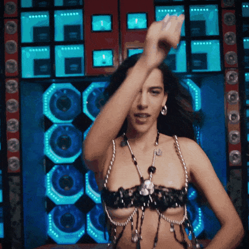 a woman in a very revealing top is dancing in front of speakers