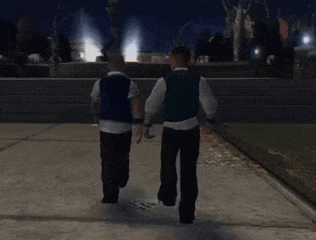 two men are walking down a sidewalk holding hands at night
