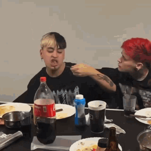 a bottle of coca cola sits on a table next to a man eating