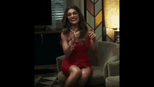 a woman in a red dress is sitting in a chair laughing .