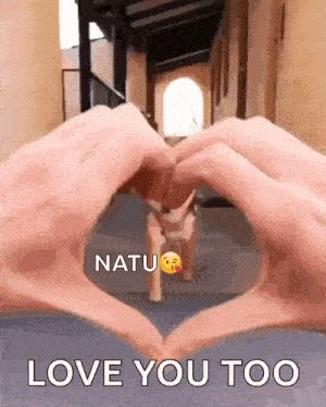 a person is making a heart shape with their hands in front of a dog that says love you too