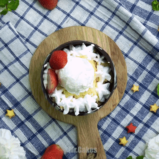 a bowl of ice cream with strawberries and whipped cream on a wooden cutting board with mr.cakes written on the bottom