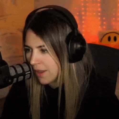 a woman wearing headphones is sitting in front of a microphone and smiling .
