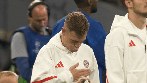 a man wearing a white adidas jacket with a bayern munich logo on his chest