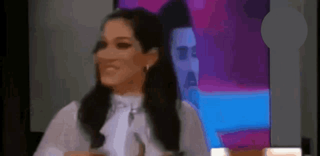 a woman in a white shirt is smiling in front of a painting of a man .