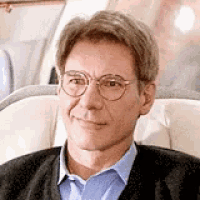 a man wearing glasses is sitting in a chair on a plane and smiling .