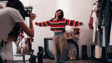 a woman taking a picture of a woman in a striped sweater