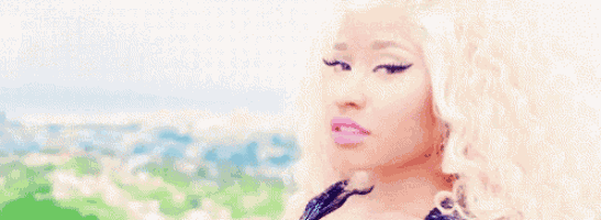 a woman with blonde hair and pink lipstick is standing in front of a field of flowers .