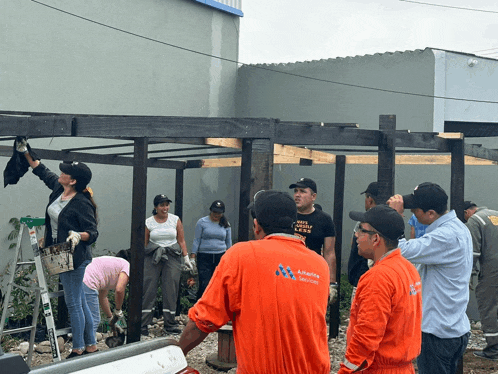 a group of people are working on a wooden structure and one of the men is wearing a shirt that says aguila