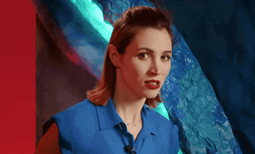 a woman in a blue shirt is standing in front of a blue wall