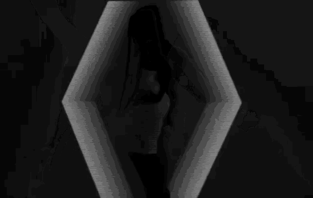 a black and white photo of a woman dancing in front of a projection of arrows .