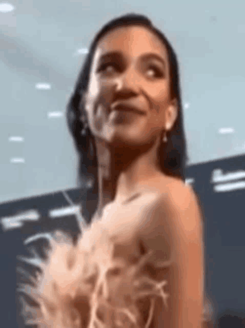 a woman in a feathered dress is smiling .