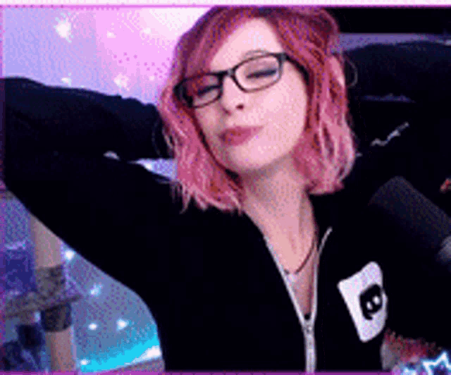 a woman with pink hair and glasses is standing in front of a microphone