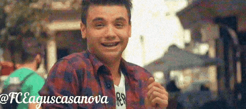 a man in a plaid shirt is smiling and giving a thumbs up sign