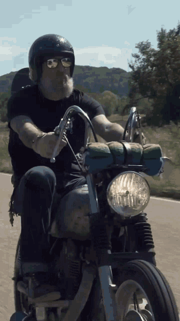 a man wearing sunglasses and a helmet is riding a motorcycle on a road